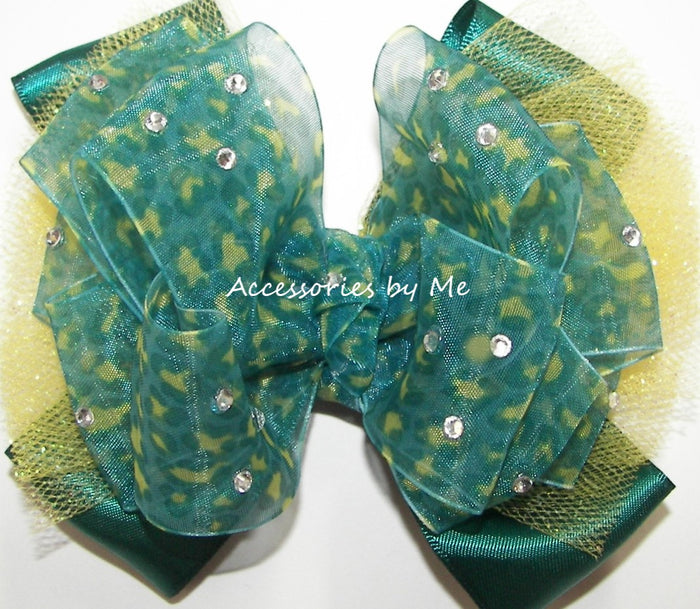 Green and yellow decorative bow with rhinestones on a white background, labeled 'Accessories by Me'.